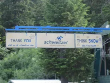 A Schweitzer Mountain Resort sign reading Think Snow at the top of the chairlift.