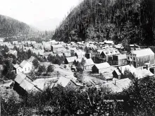 Historic photograph of Murray, Idaho, circa 1890 — the gold-rush boomtown in the Coeur d'Alene Mining District, its wooden buildings filling the valley along Prichard Creek beneath forested slopes.