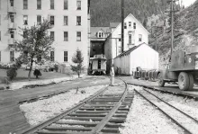 Historic photograph of the Tiger Hotel in Burke, Idaho, with railroad tracks running through the hotel in the narrow Burke Canyon.