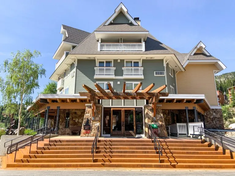 The Chimney Rock Grill entrance in the Selkirk Lodge at Schweitzer village, with wide wooden steps leading up to its stone and timber entryway.