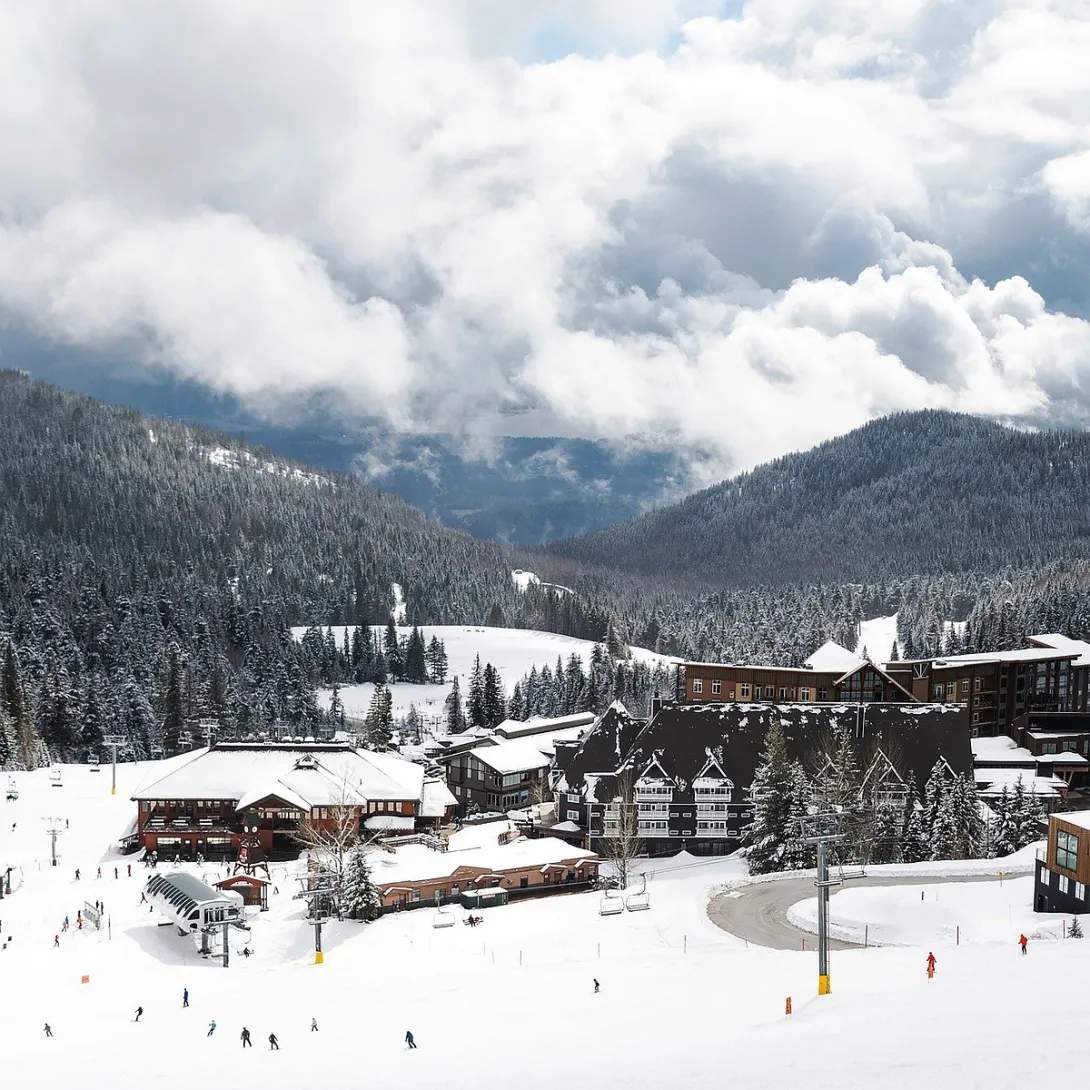 Schweitzer Mountain Resort village in winter, with skiers on the slopes below the village lodges and lifts