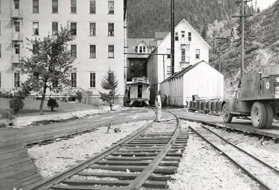Historic photograph of the Tiger Hotel in Burke, Idaho, with railroad tracks running through the hotel in the narrow Burke Canyon.
